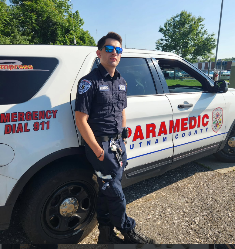 A man in uniform stands in front of a paramedic fly car.
