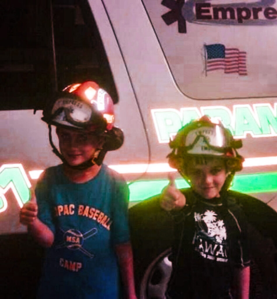 Twp children in helmets stand in front of a fly car.