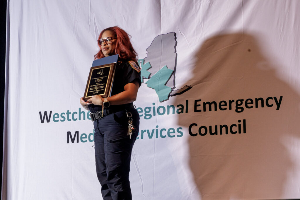 A woman stands on stage with a plaque after winning award.